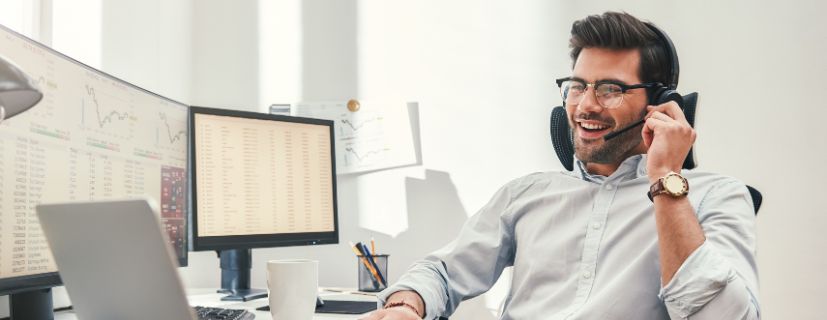 Homem conversando no celular no escritório sentado na frente do computador