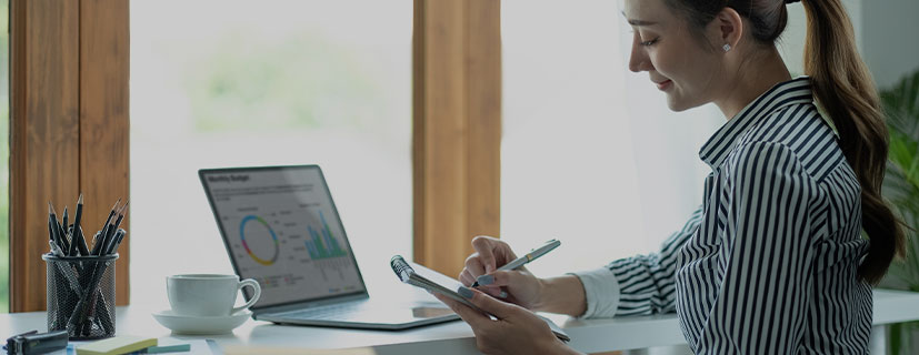 Mulher trabalhando na sua mesa de escritório e calculando o lucro de e-commerce