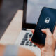 imagem de uma mão feminina mexendo no celular em frente a um notebook