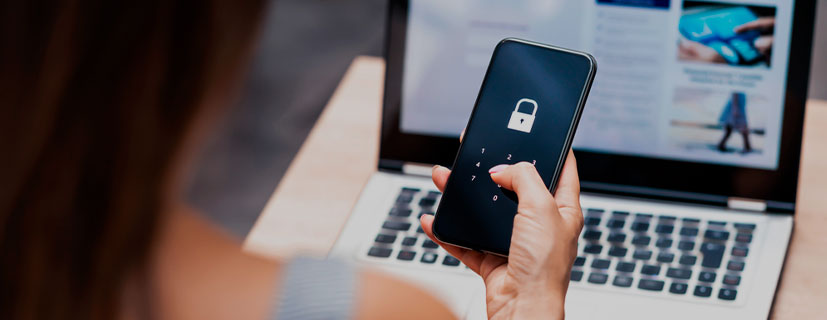 imagem de uma mão feminina mexendo no celular em frente a um notebook