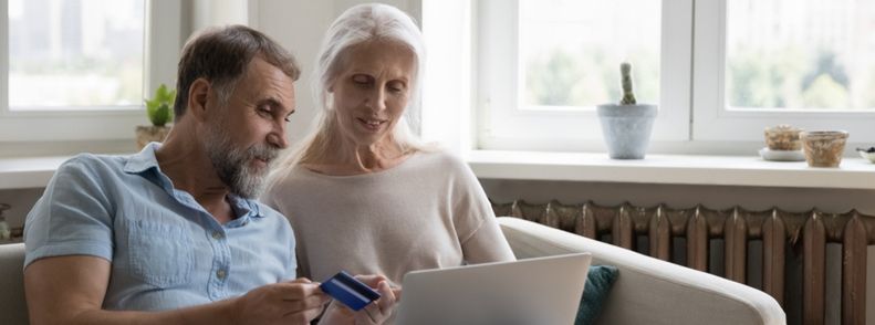 Imagem de homem e mulher sentados no sofá fazendo um compra no notebool