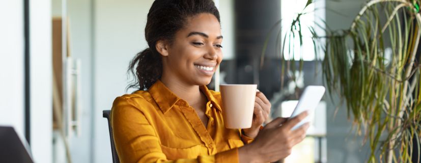 Mulher segurando uma xícara enquanto usa o celular